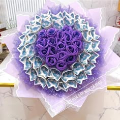 a purple and white paper flower on top of a box with money in the center