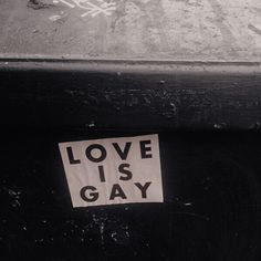 a piece of paper with the words love is gay written on it next to a suitcase