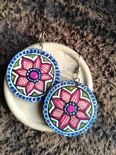 a pair of earrings with flowers painted on them