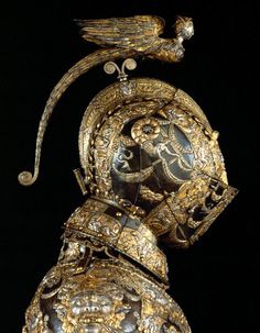 an intricately decorated gold and silver object with birds perched on it's head