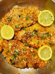 two pieces of fried fish with lemons and parsley in a frying pan