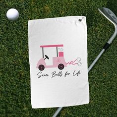 a golf ball and club on the grass with a towel that says some balls for life