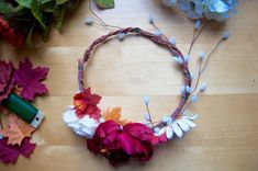 a wreath made out of flowers and leaves on top of a wooden table next to scissors