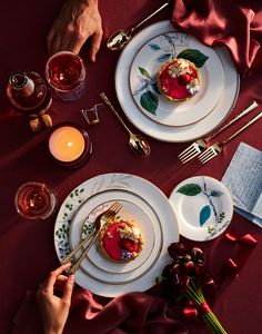 two white plates topped with food on top of a table next to candles and napkins