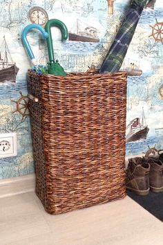 a basket with umbrellas and other items in it on the floor next to a wall