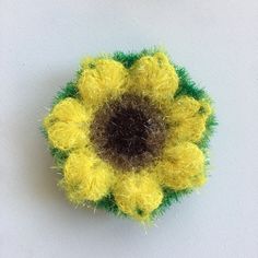 a yellow and green brooch sitting on top of a white surface