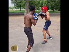 two young men are practicing boxing in the park