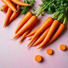 carrots and parsley laid out on a pink surface