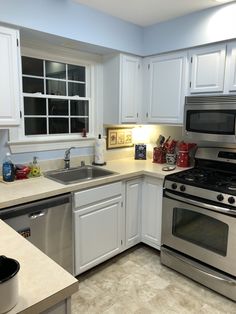 a kitchen with white cabinets and stainless steel appliances, including an oven, dishwasher, sink, microwave, and stove