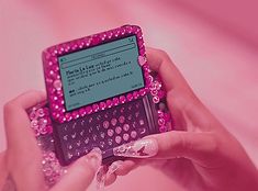 a person holding a pink and black electronic device in their hands with lots of beads on it