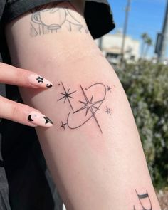 a woman's arm with tattoos on it and stars in the sky above her