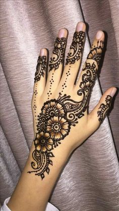 a woman's hand with henna tattoos on it