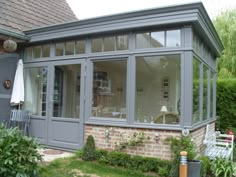 a house that has been painted gray and is in the yard with some plants around it