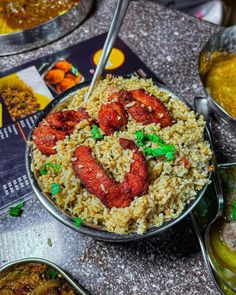 a bowl filled with rice and sausage on top of a table next to other dishes