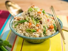 a bowl filled with rice and vegetables next to chopsticks on top of a table