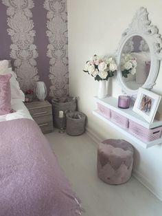 a white and purple bedroom with flowers on the nightstands, pink bedding and decorative wallpaper