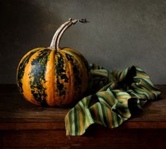 a large pumpkin sitting on top of a wooden table next to a green and yellow striped napkin