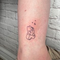 a small teddy bear tattoo on the ankle