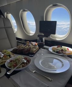 the table is set with food and wine for two people to enjoy on an airplane