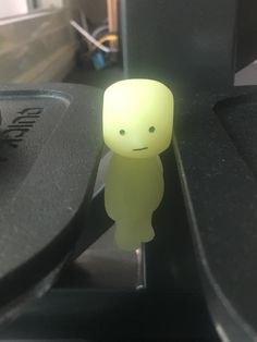 a small yellow toy sitting on top of a black table next to a computer keyboard