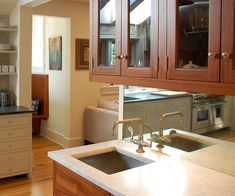 a kitchen with wooden cabinets and stainless steel sink in front of an open door leading to the living room