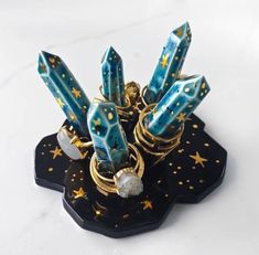 a bunch of rings sitting on top of a black stand with gold stars and pearls