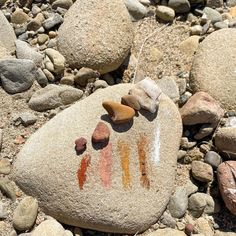 a rock with some writing on it sitting in the sand next to rocks and gravel