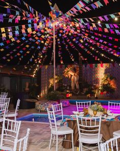 an outdoor party with tables and chairs set up in front of a pool at night