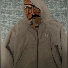 a gray sweatshirt with a checkered hoodie on it and a tag hanging from the front