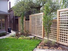 a wooden fence in the middle of a yard with grass and rocks on the ground