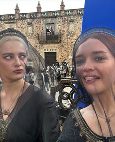 two women with veils on their heads are standing in front of an old building