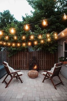 two lawn chairs sitting on top of a brick patio next to an open fire place