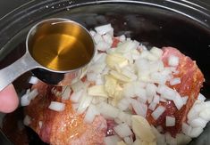 someone is adding onions and meat to the slow cooker