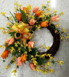 a wreath with orange and yellow flowers sitting on the floor in front of a wall