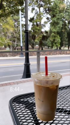 a cup of coffee sitting on top of a metal table next to a lamp post