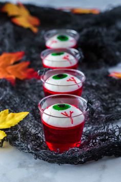 three cups filled with jello sitting on top of a black cloth covered tablecloth