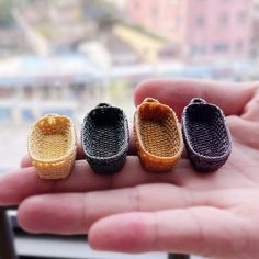 three miniature crocheted shoes sitting on top of someone's hand in front of a window