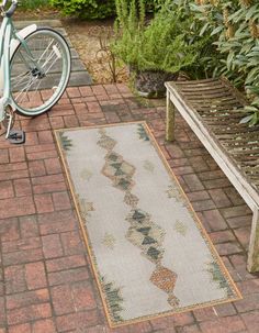 a bicycle is parked next to a bench on a brick walkway in front of some plants