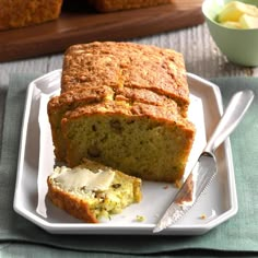 there is a loaf of bread on the plate with butter and spoons next to it