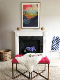 a living room with a white fireplace and red bench in front of it on carpeted floor