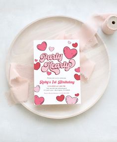 a paper party card on a plate with some pink ribbon and two rolls of toilet paper