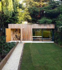 a bike is parked in the open door of a small wooden building with grass and trees surrounding it