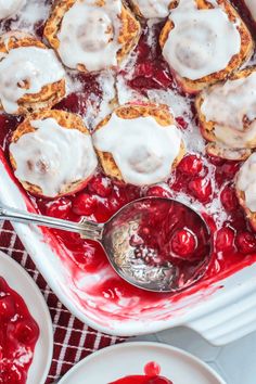 a pan filled with desserts covered in icing and cranberry sauce on top of a table