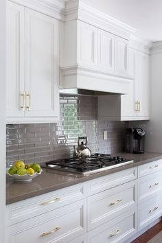 a kitchen with white cabinets and stainless steel counter tops is pictured in this image, there are two bowls of fruit on the stovetop