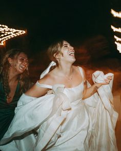 two women dressed in white are laughing together