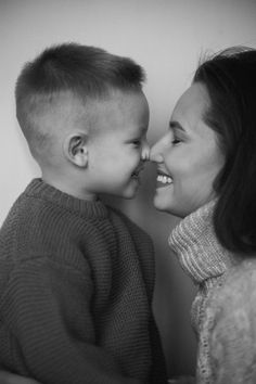 black and white photograph of a mother kissing her son's forehead while he is wearing a sweater