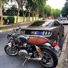 the motorcycle is parked on the side of the road next to the car in the street