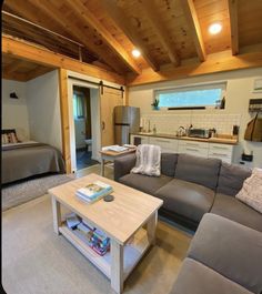 a living room filled with furniture next to a bed and a kitchen area in the background