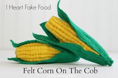 two corn cobs with green leaves on the top and bottom, sitting next to each other