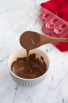 a spoon is pouring chocolate into a bowl